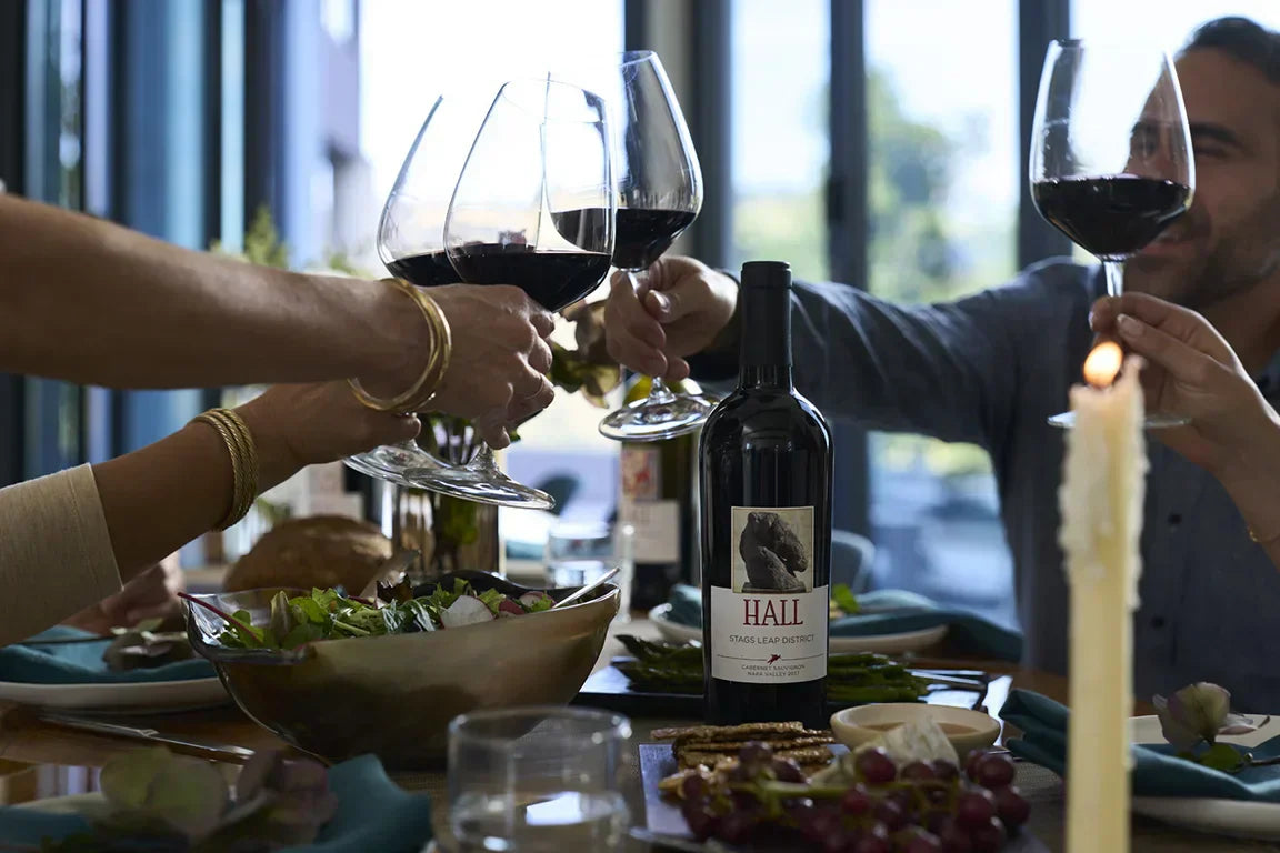 Full wine glasses coming together to cheers at the dinner table