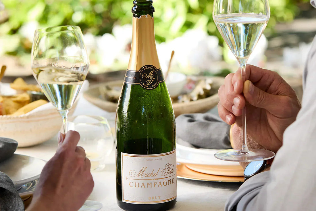 Two glasses of Champagne at the table with a bottle of Michel Foch Champagne