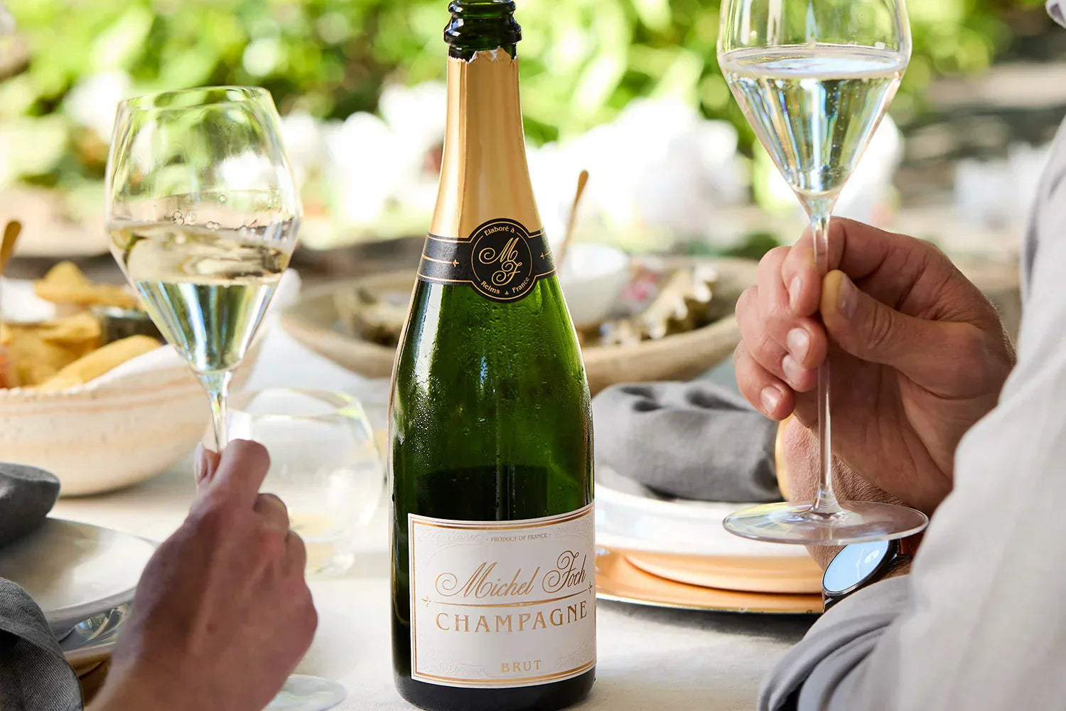 Two glasses of Champagne at the table with a bottle of Michel Foch Champagne