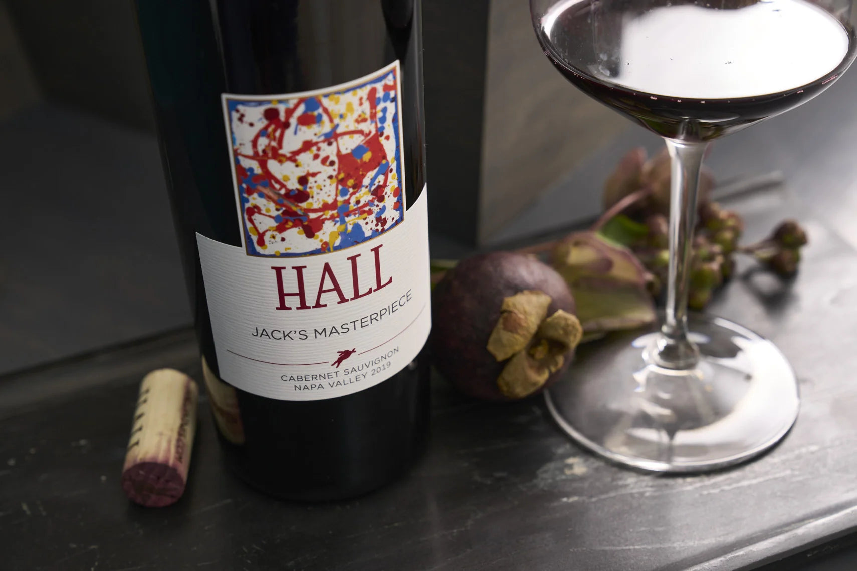 A hand reaching to select a wine bottle from a cellar rack.