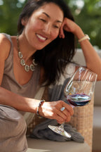 Woman smiling while holding a glass of 2021 HALL Eighteen Seventy-Three Cabernet Sauvignon