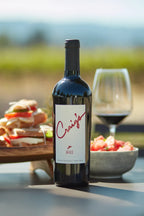Photo of a bottle of 2019 HALL Craig's Cabernet Sauvignon on a picnic table with a platter of sandwiches, a summer salad, and glass of red wine in the background.
