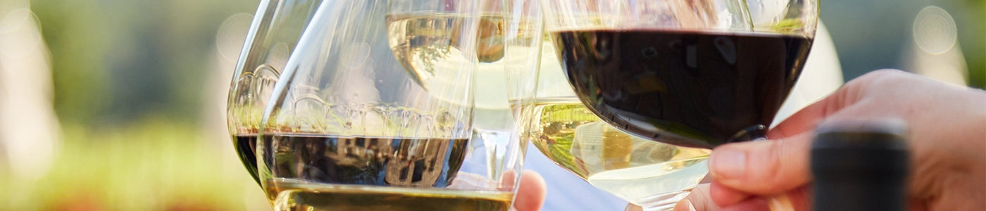 Four wine glasses toasting to an occasion against a blurred background.