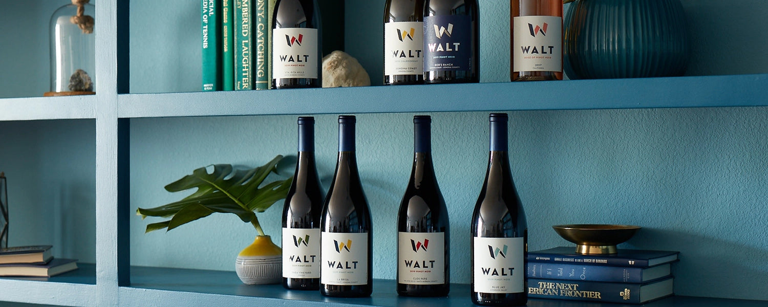 Wine bottles with 'WALT' label on a shelf with decorative items