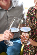Smiling couple toasting with glasses of 2019 HALL Craig's Cabernet Sauvignon