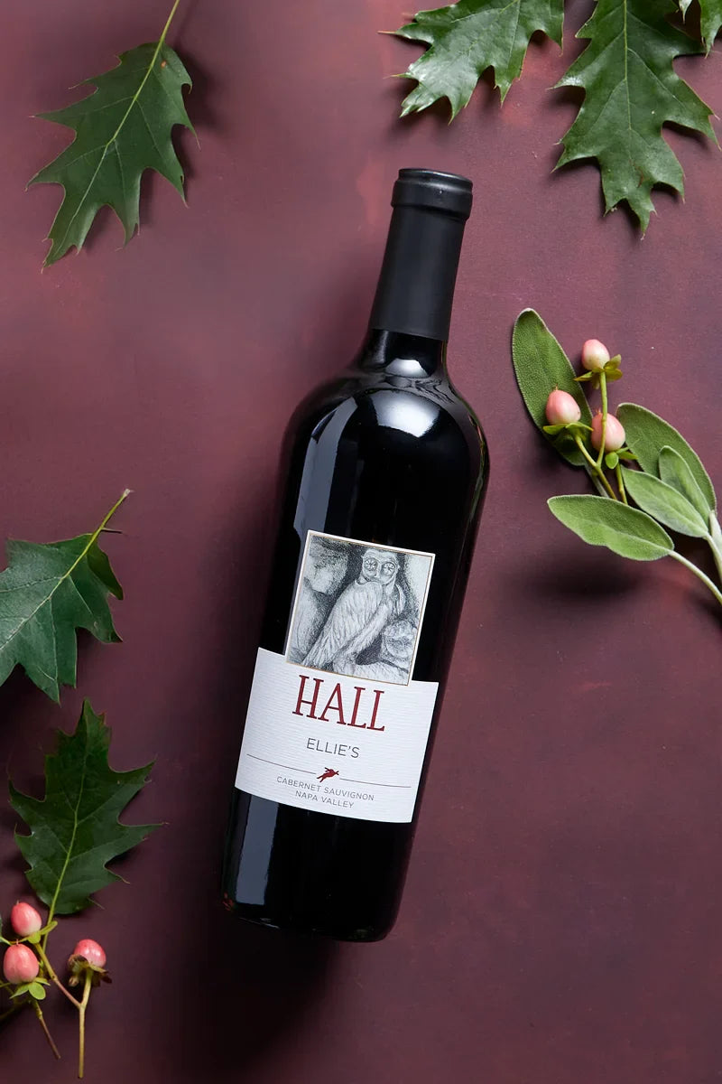 2021 HALL Ellie's Cabernet Sauvignon bottle on red fabric with surrounding foliage
