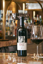 2022 HALL Ellie's Cabernet Sauvignon bottle on granite bartop with glass of red wine, bar back with liquor bottles and beer taps in background