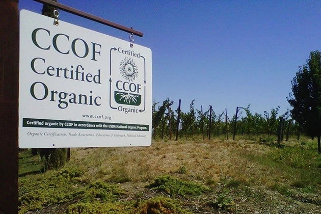 CCOF Certified Organic sign in a field with trees and clear sky