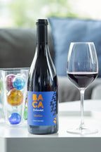 Bottle of Baca Marbles wine with a glass of red wine on a table.