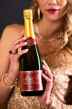 Woman wearing an elegant dress holding a bottle of Michel Foch Brut Champagne 2013 Vintage.