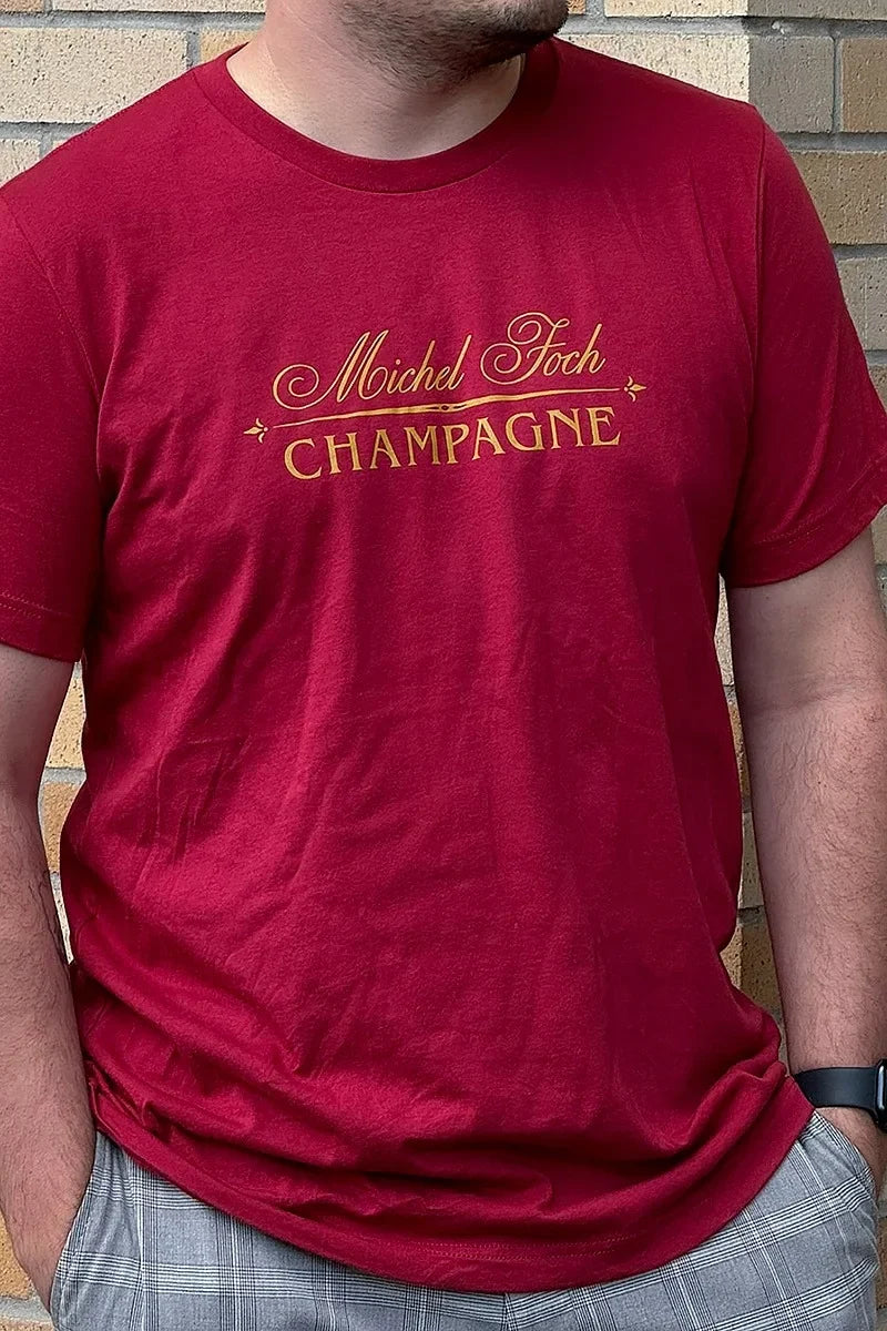 A man wearing a dark red Michel Foch Champagne logo shirt.