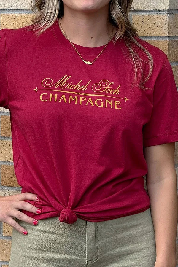 A woman wearing a dark red Michel Foch Champagne logo shirt