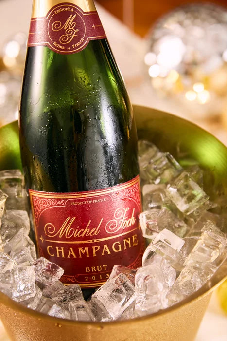 Bottle of Michel Foch Burt Champagne 2013 Vintage in a gold ice bucket.