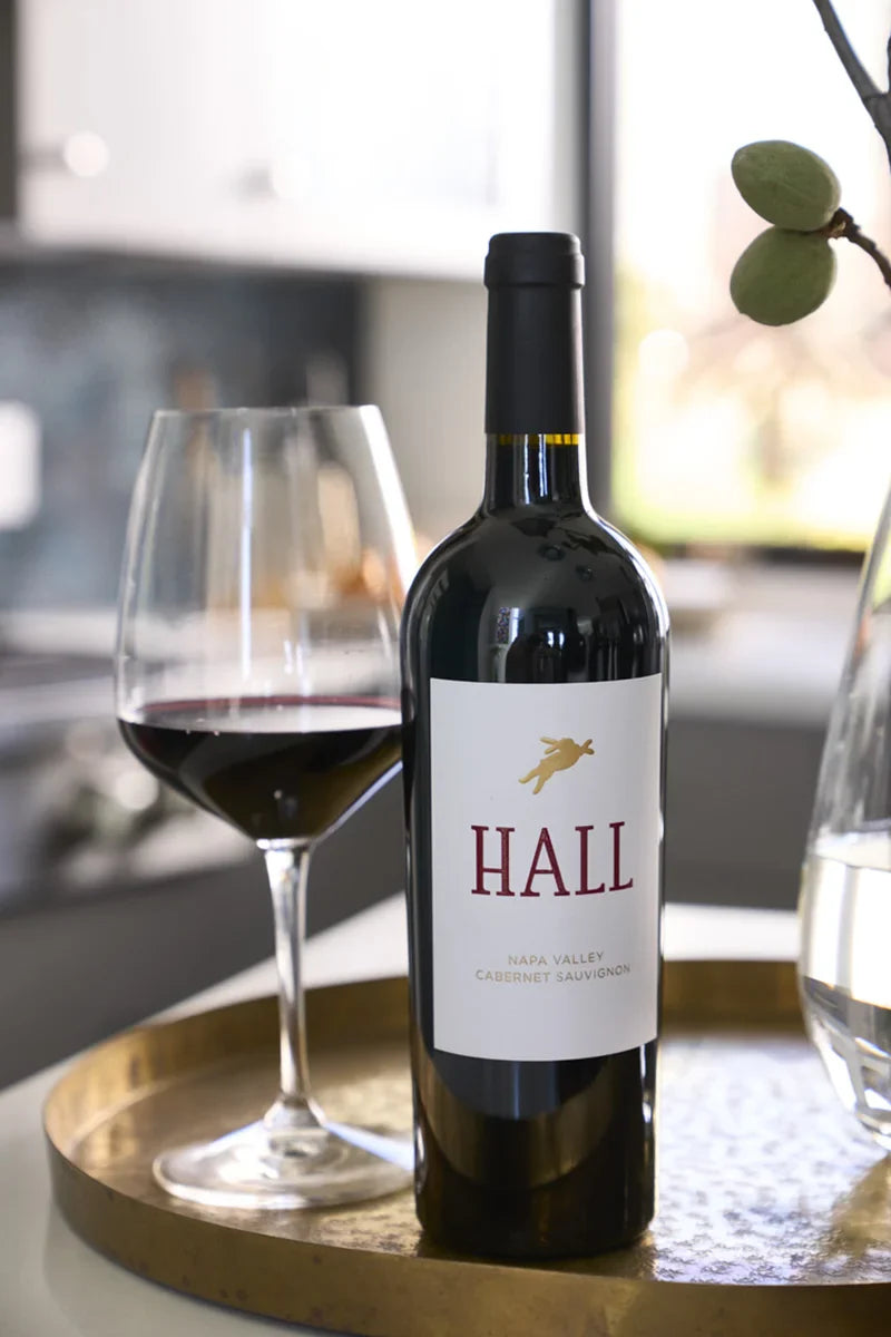 Bottle of HALL Napa Valley Cabernet sauvignon next to a glass of red wine