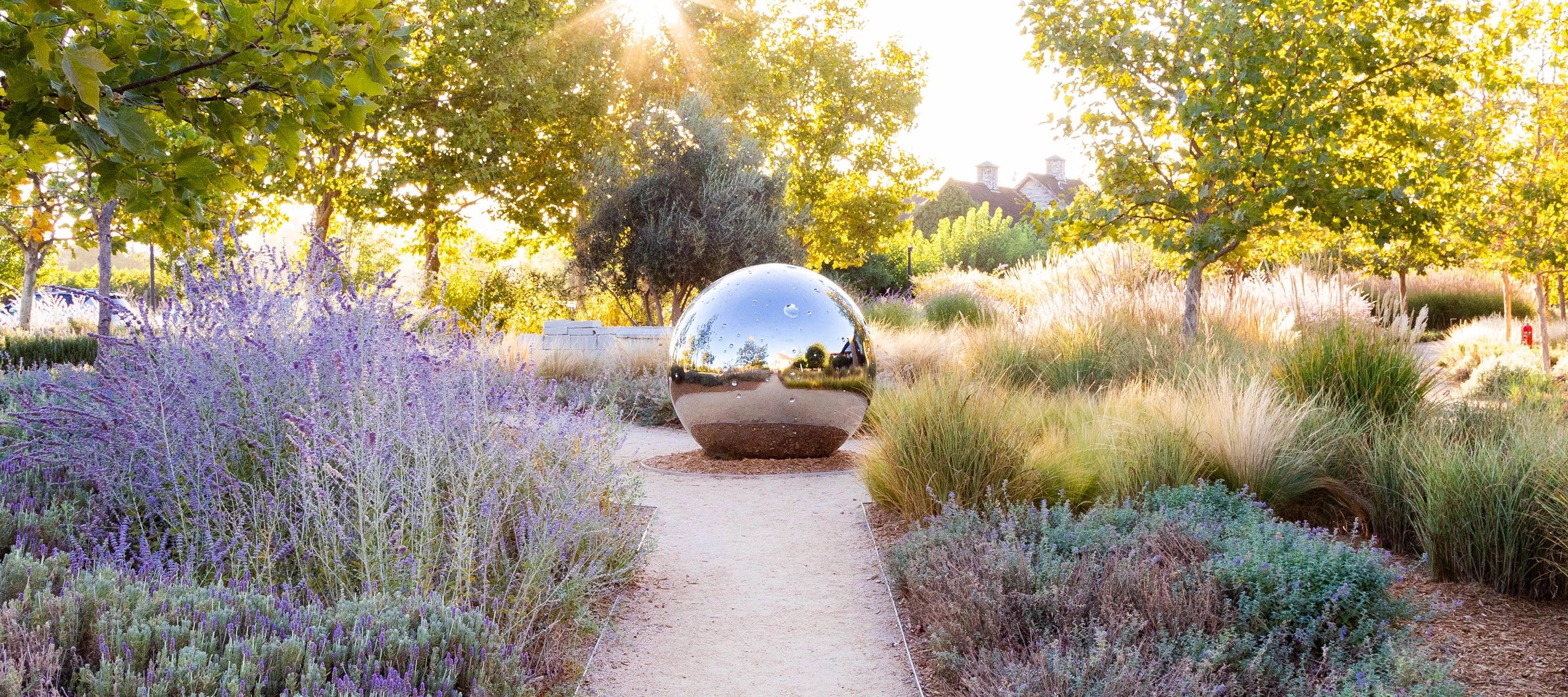 Reflective sculpture in a garden with lavender and trees