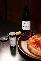 Anderson 10 spice on a black counter top with a pepperoni pizza and bottle of WALT Blue Jay Pinot Noir.