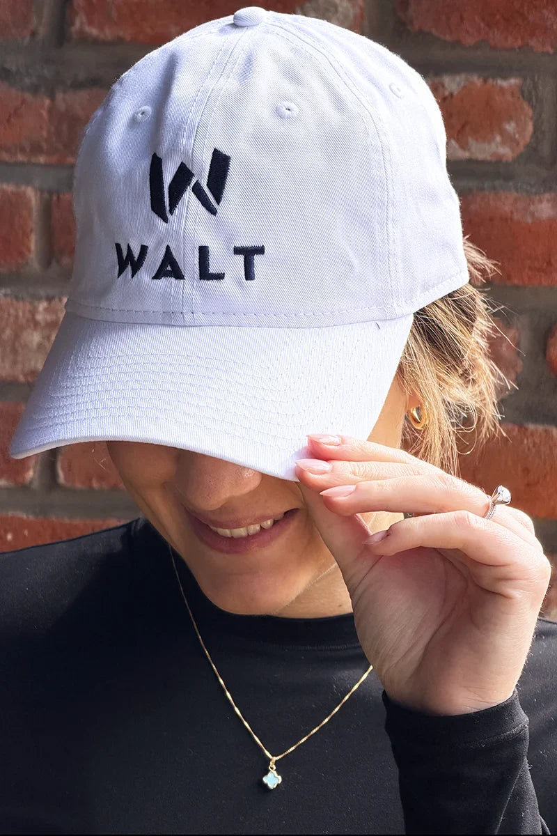 Image of a person wearing a New Era white cap with the WALT Wines logo on the front.